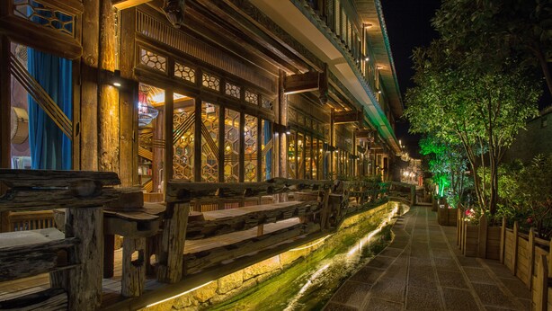 Un bâtiment traditionnel en bois, doté d’un chemin en pierre et agrémenté d’un élément décoratif aquatique.