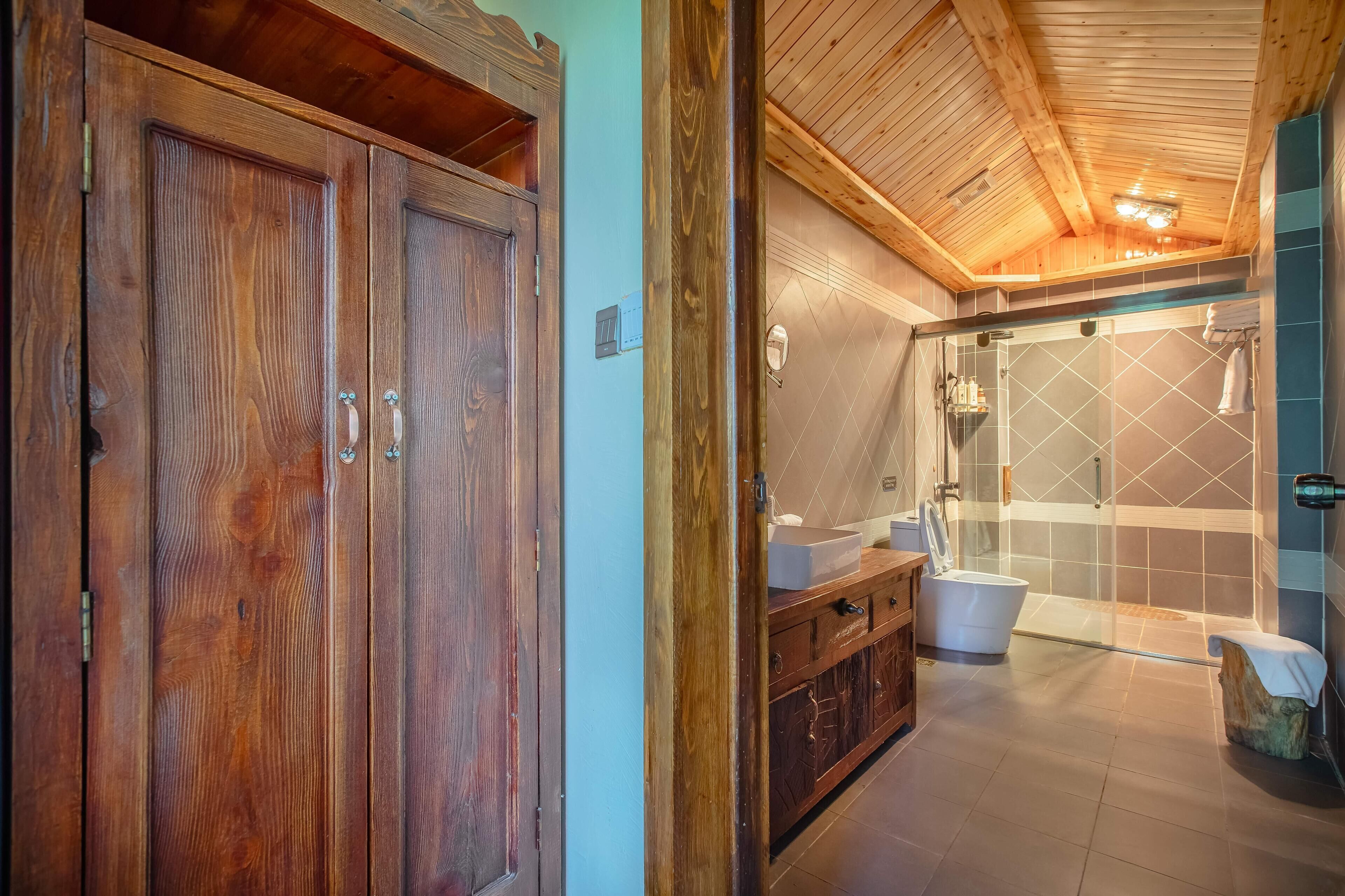 A wooden wardrobe, a bathroom with a bathtub, and a shower area.