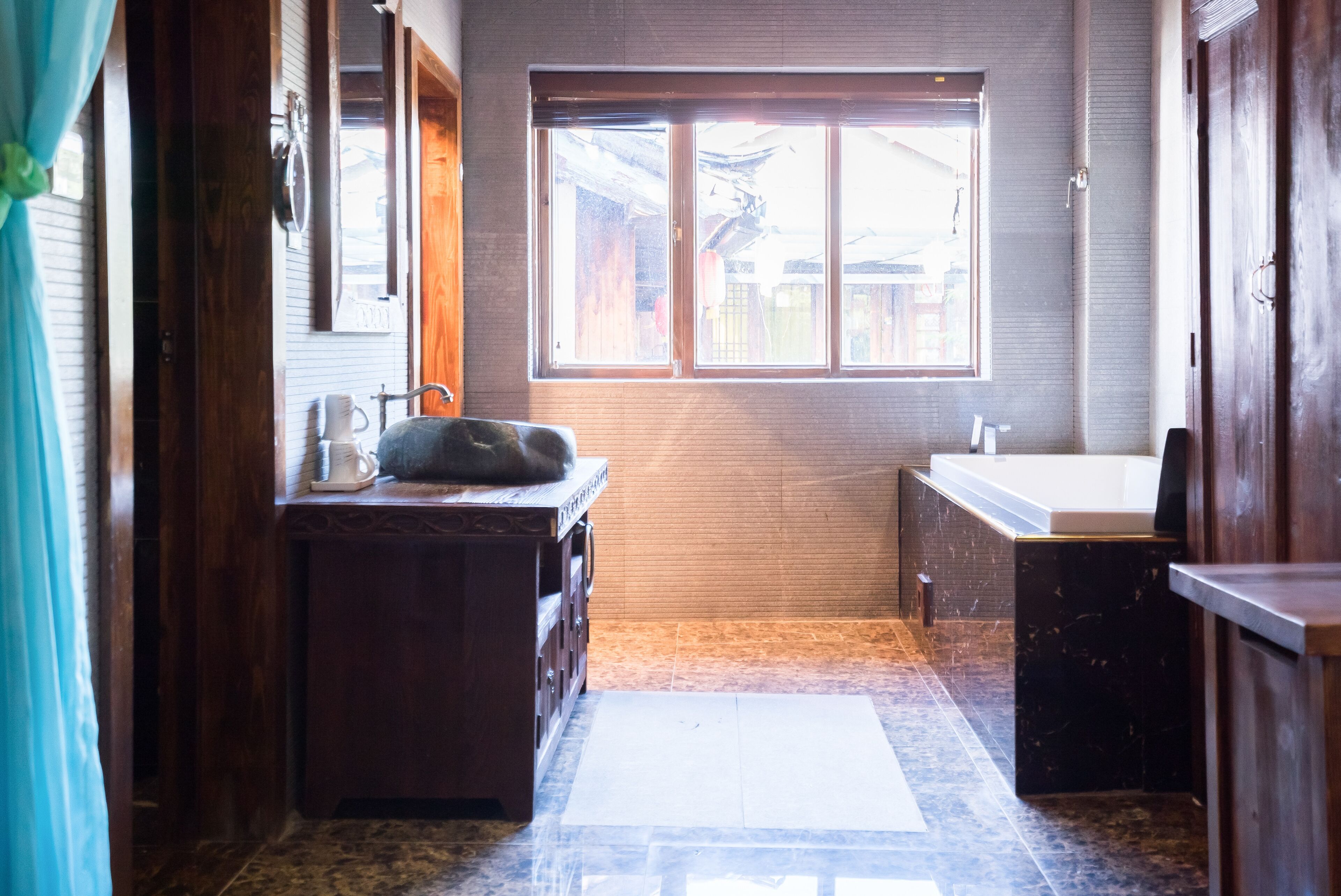 A bathroom with a wooden vanity, a sink, and a window.
