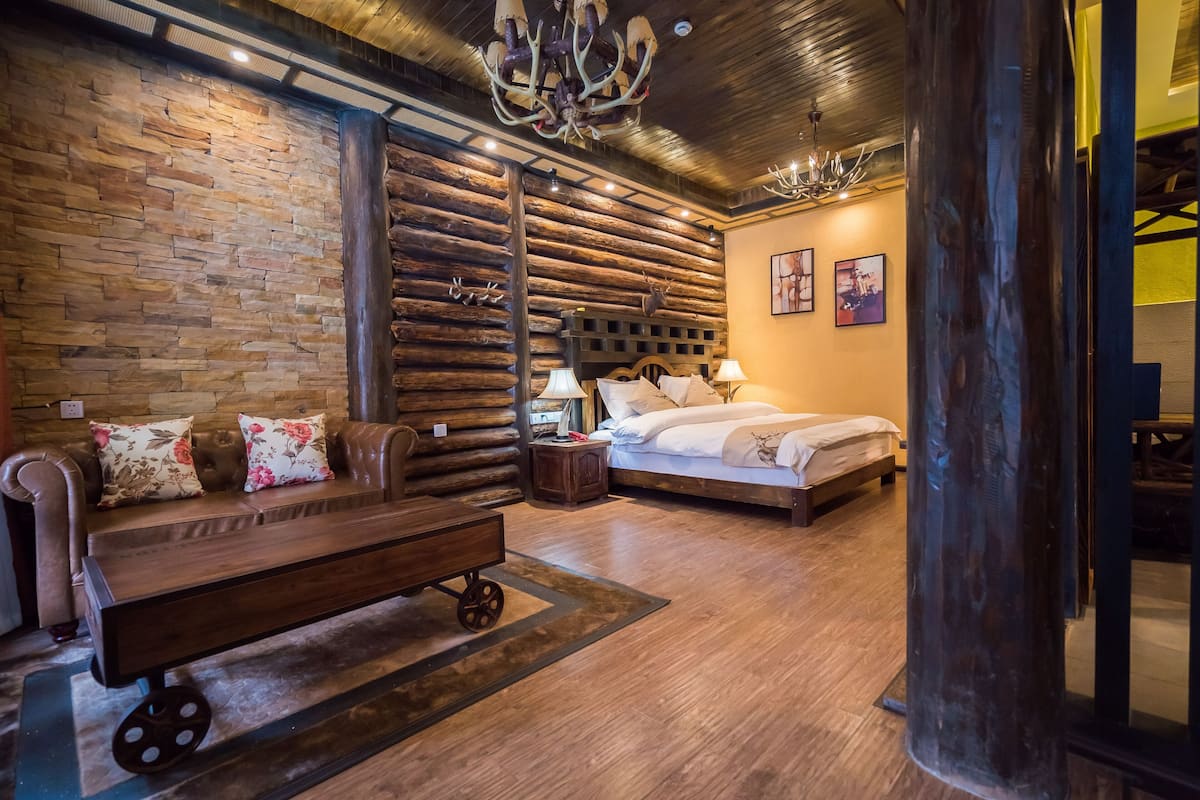 Ein rustikaler Raum mit Steinwand, Holzverkleidung, einem Bett mit Kopfteil, einer Bank und einem Wagen.