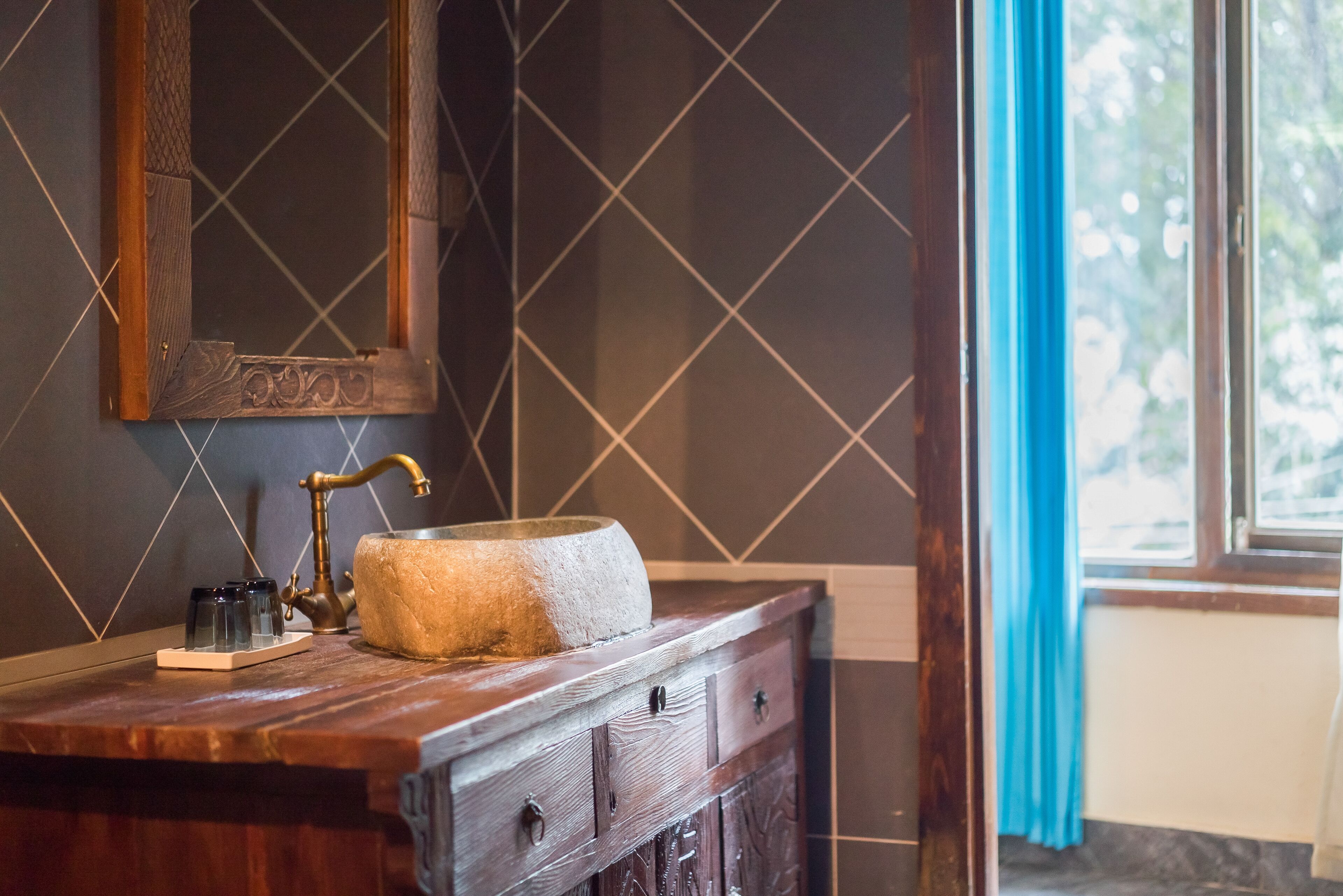 A bathroom with a wooden vanity, a large mirror, and a stone basin.