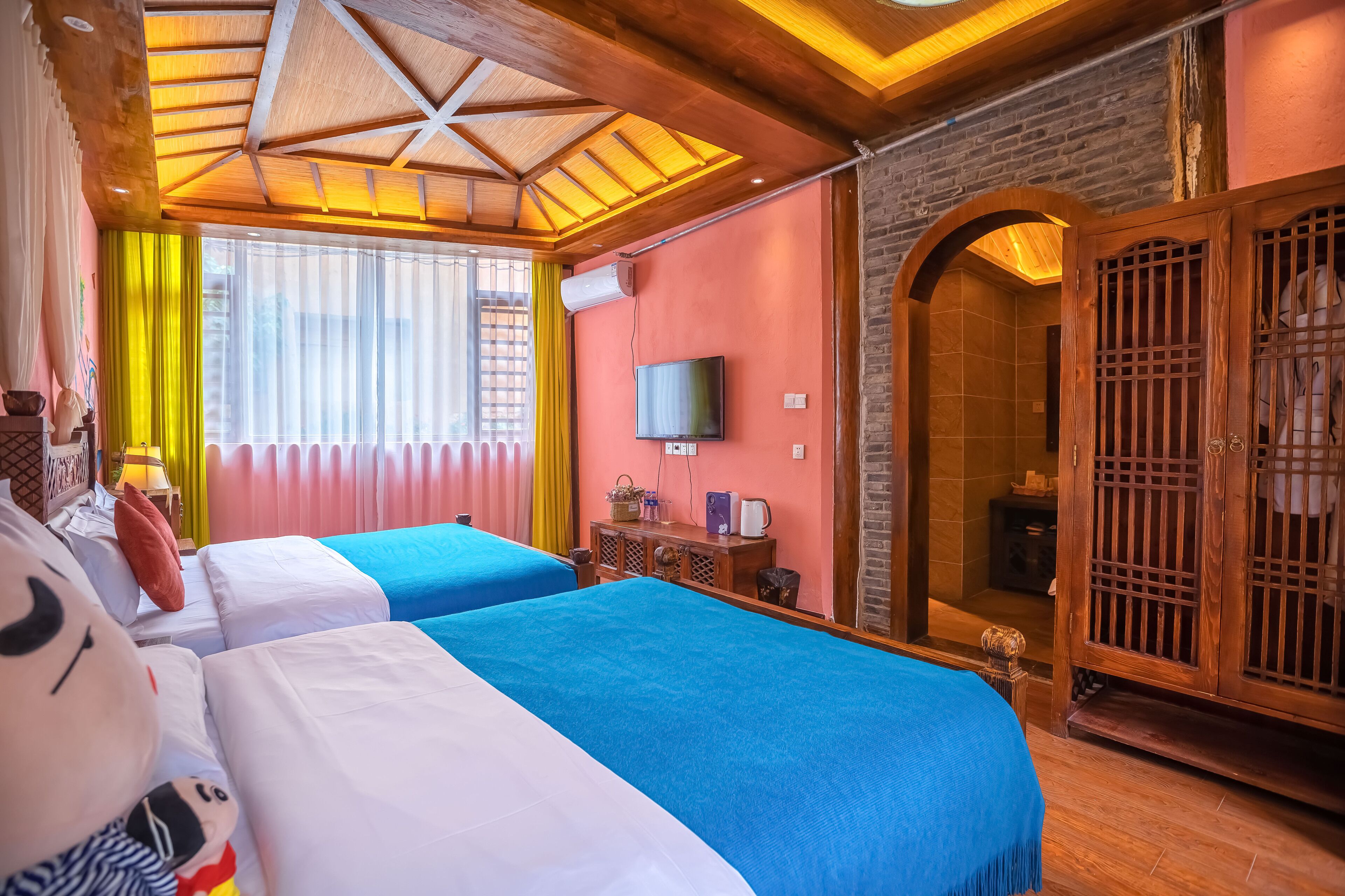 Habitación de hotel con dos camas, televisión y armario de madera.