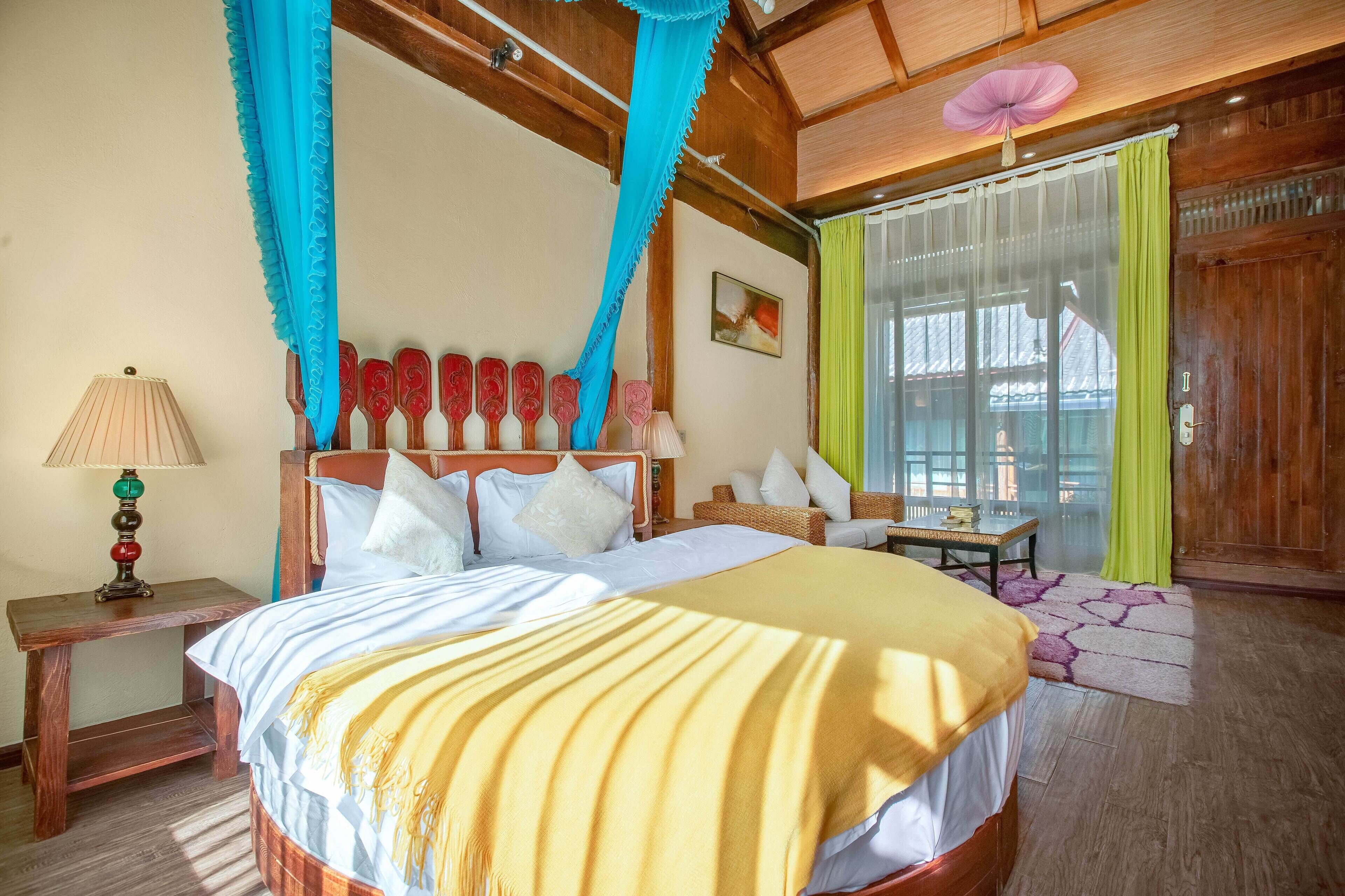Un dormitorio con cama, mesita de noche, lámpara y cortinas.