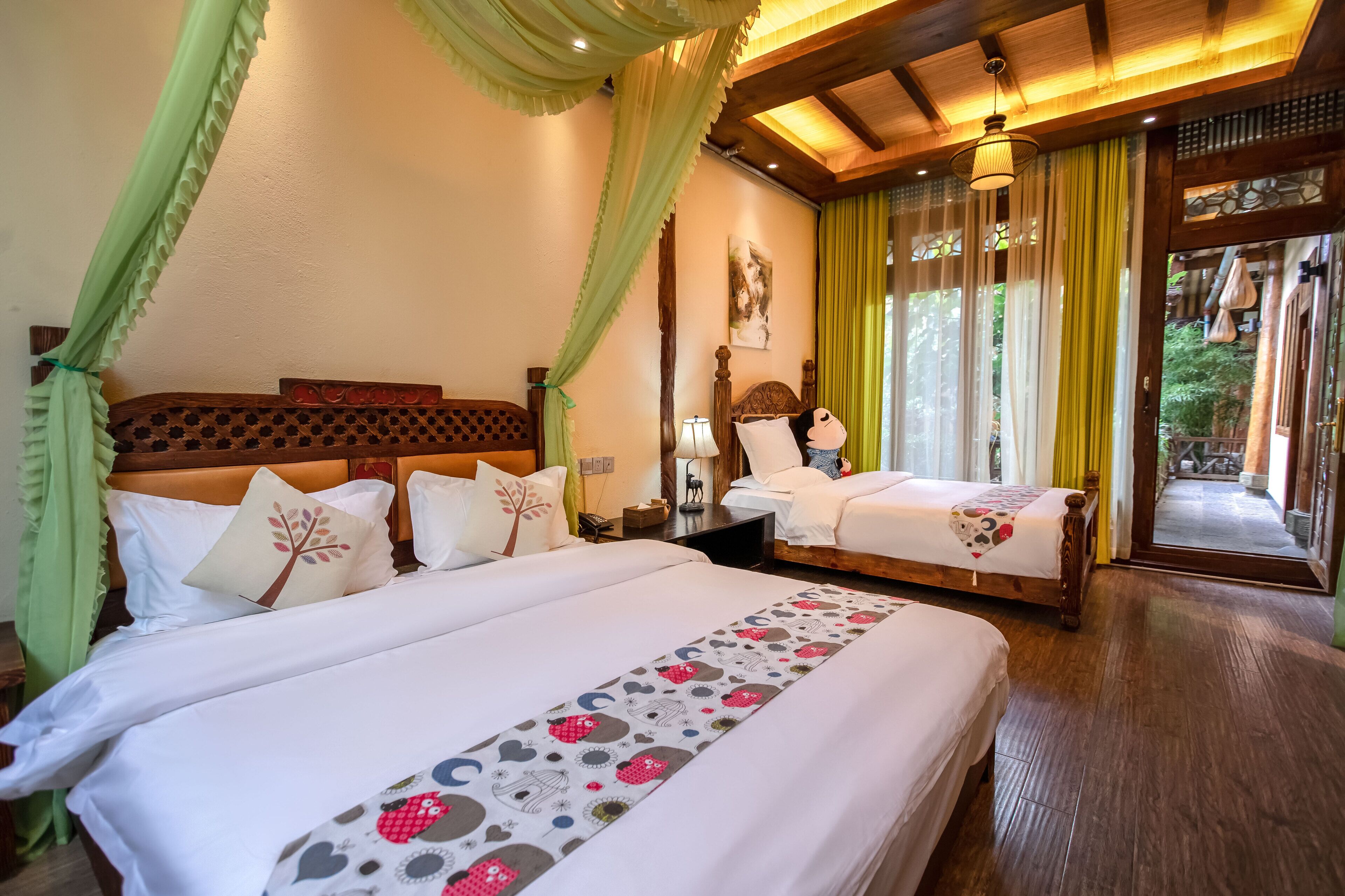A double room with two beds, a wooden headboard, a nightstand, a lamp, and a window with curtains.