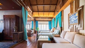 Une pièce spacieuse avec un plafond en bois, un grand canapé, un lit et un bureau.