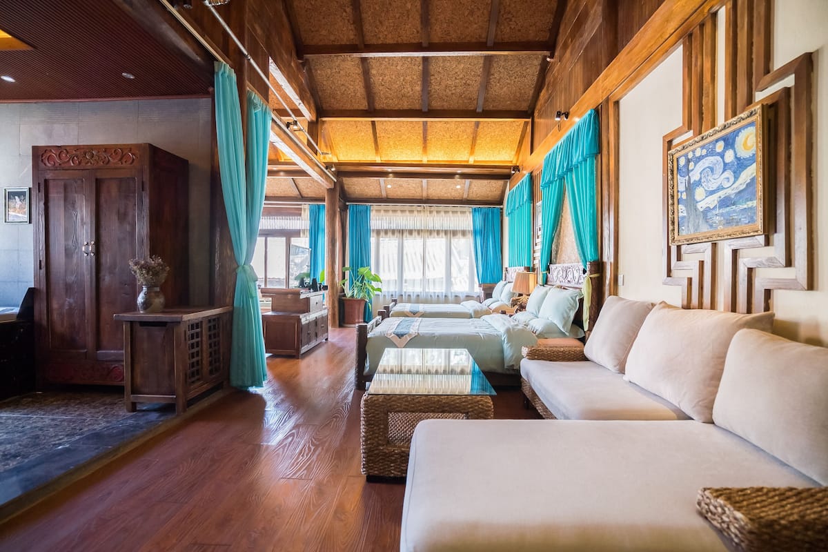 Ein geräumiges Zimmer mit Holzbalkendecke, einem großen Sofa, einem Bett und einem Schreibtisch.