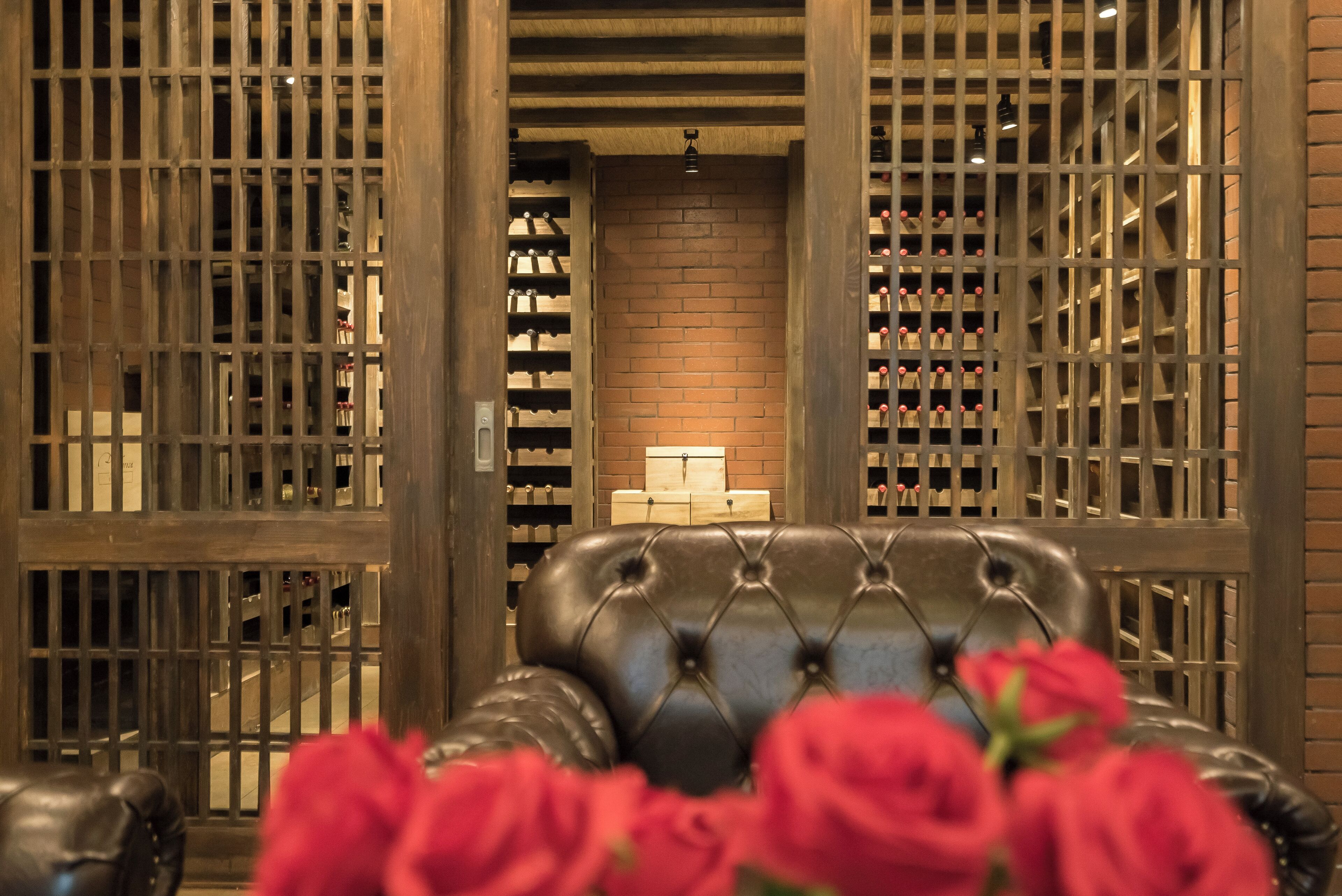 Una habitación con un sillón de cuero, una pared de ladrillo y una vinoteca con botellas.