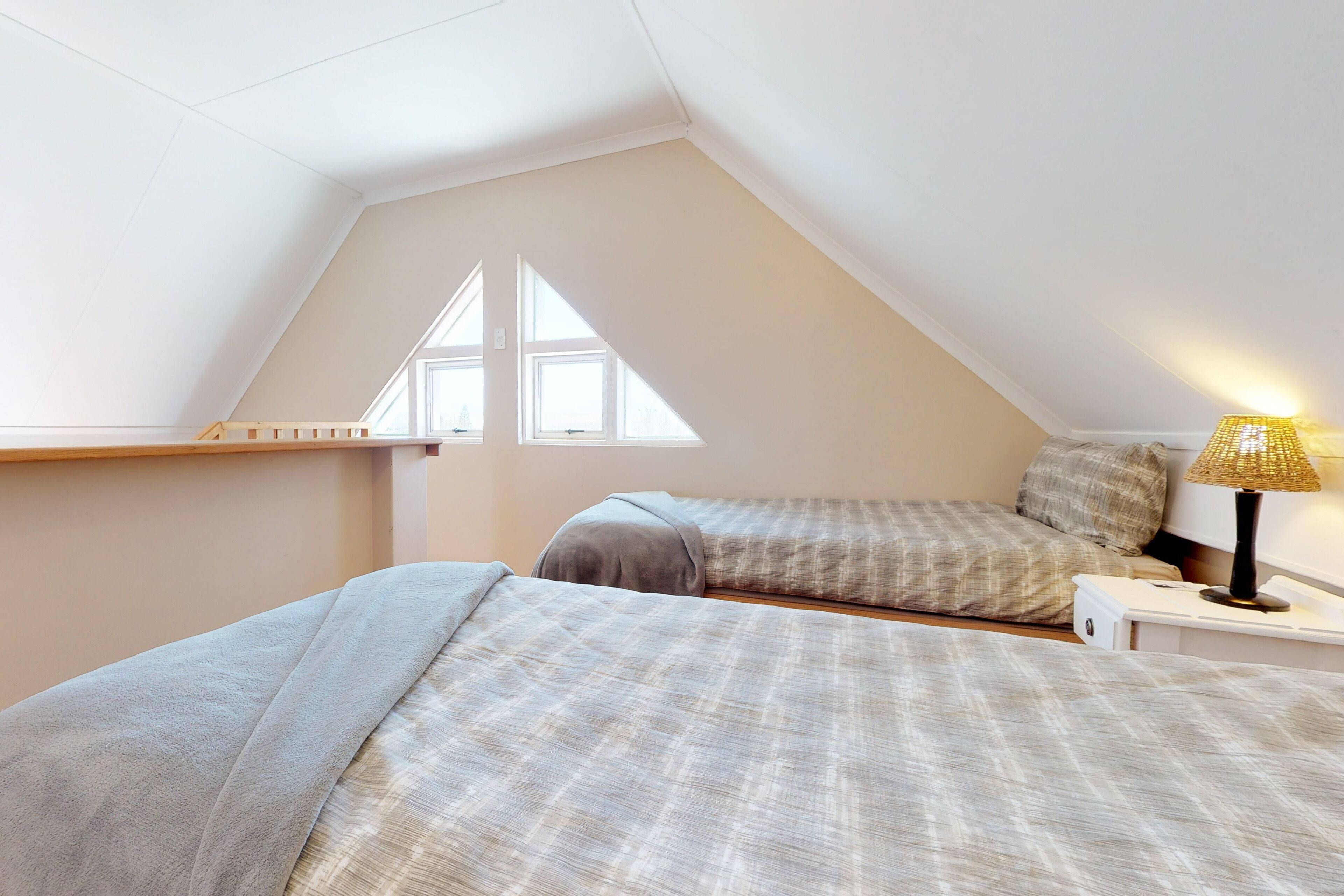 A bedroom with two beds, a window, and a bedside lamp.
