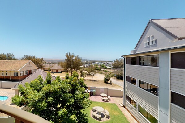 A residential building with a large window, a swimming pool, and a well-maintained lawn.