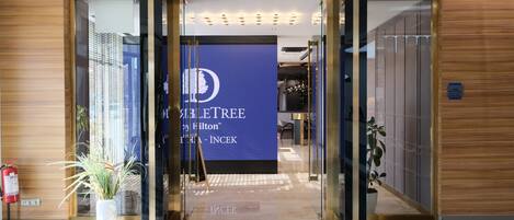 A hotel entrance with a blue banner displaying the name 'HILTON' and 'HILTON INCEK'.