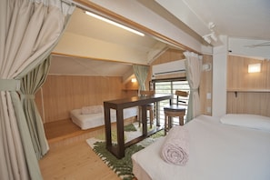 A cozy room with a bed, a small table, and a window with curtains.
