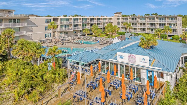 A resort with multiple buildings, a swimming pool, and outdoor seating areas. - Summer & July 4th Savings at Beachside Colony Tybee's ONLY Oceanfront Resort 3/2 (Tybee Island)