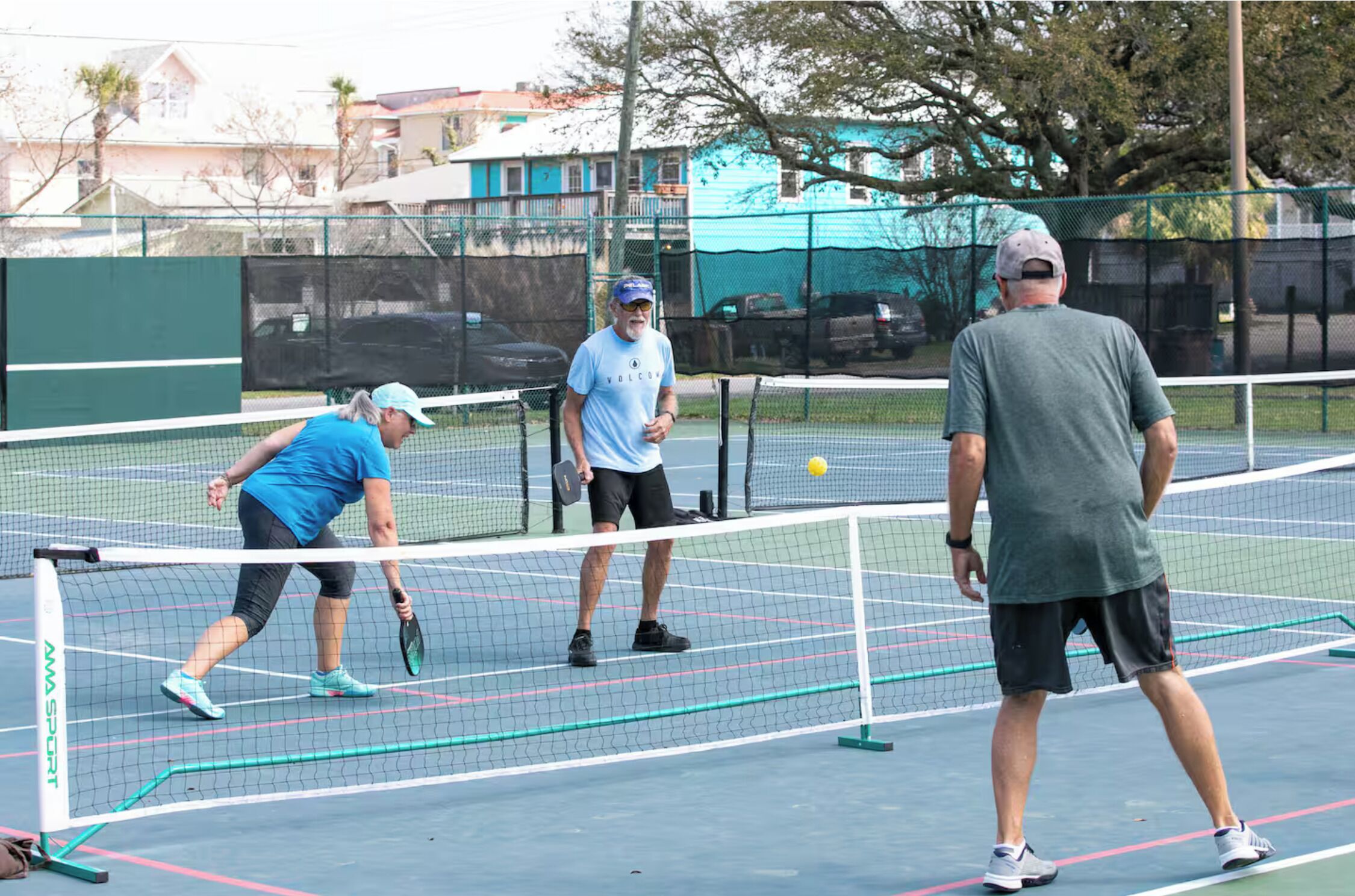 Una pista de tenis amb una xarxa, un jugador amb una samarreta blava i un altre jugador amb una samarreta gris.