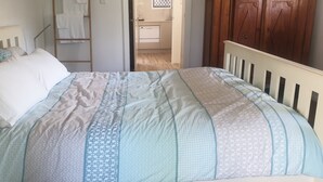 Una cama con una colcha estampada, un cabecero de madera y un almohadón blanco.