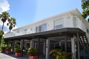 Um hotel com área externa coberta, palmeiras e céu azul límpido.