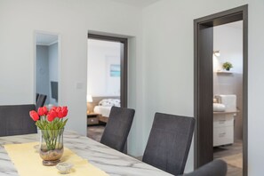 A dining area with a marble table, a vase of red tulips, and dark grey chairs. - Villa Roko (Vir)