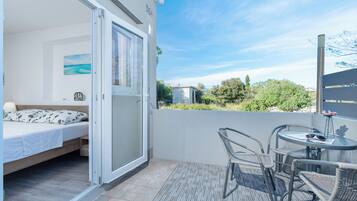 A balcony with a bed, a table, and chairs.