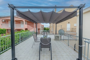 A balcony with a table and chairs, a pergola with a canopy, and a railing. - Apartments Holiday Near Beach (Vodice)