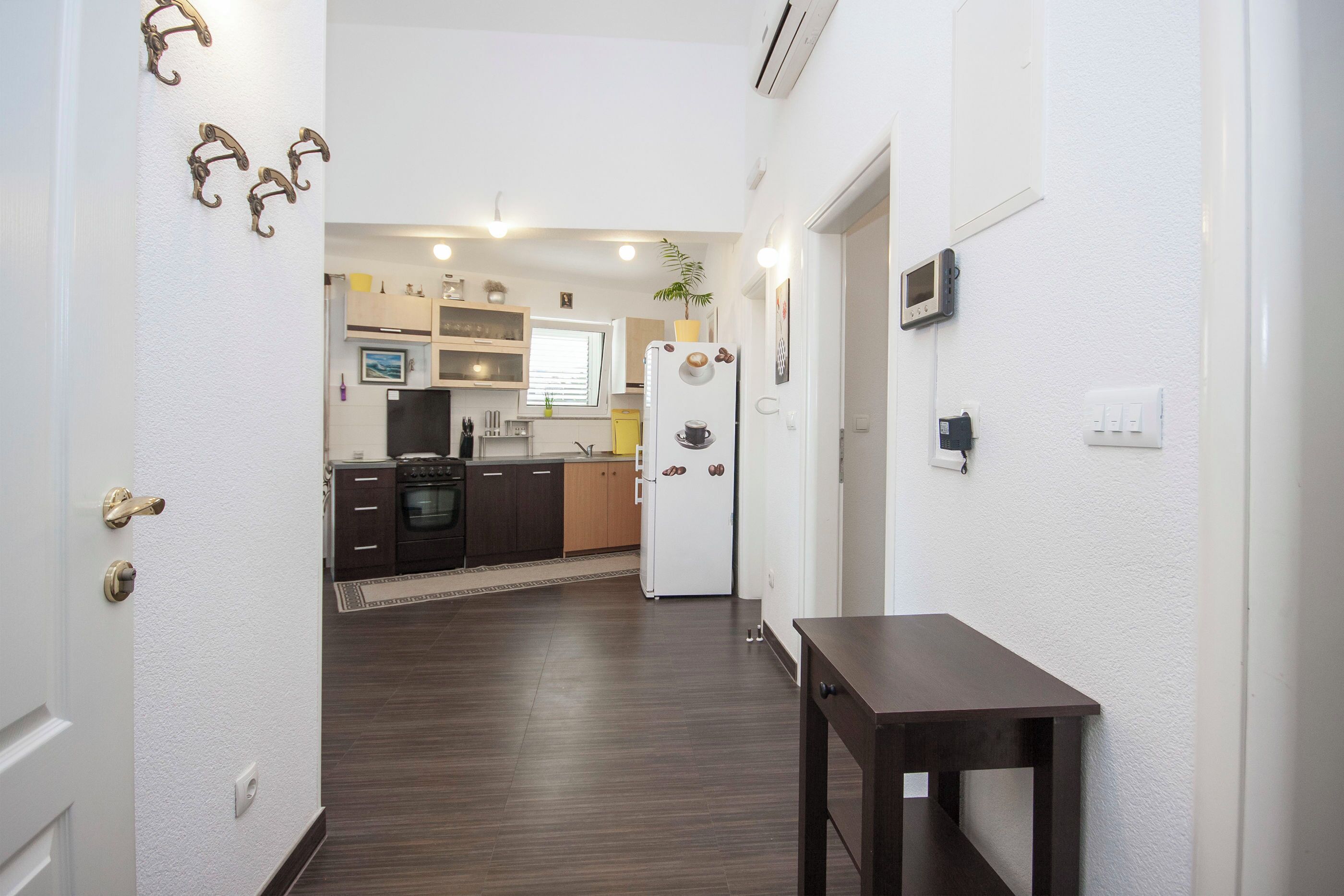 Un pasillo que conduce a una cocina con una mesa de comedor y un refrigerador.