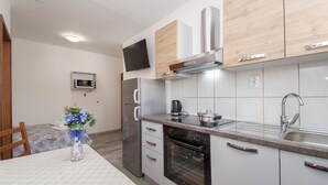 A modern kitchen with stainless steel appliances, wooden cabinets, and a flat-screen TV mounted above the counter. - Apartments Rajka (Vodice)