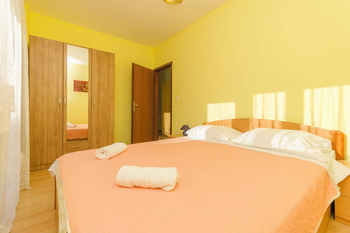 A bedroom with a bed, a wardrobe, and a door leading to another room.