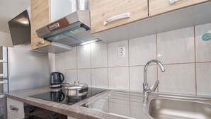 A modern kitchen with a built-in stove, a sink, and a coffee maker. - Apartments Rajka (Vodice)