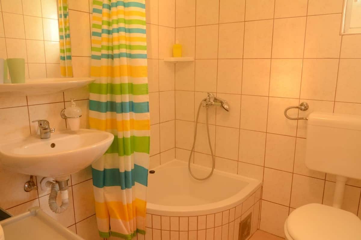 A bathroom with a sink, toilet, shower, and a striped shower curtain.