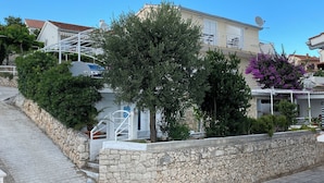 A residential area with stone walls, a paved pathway, and houses with satellite dishes. - Apartments Lumini (Okrug Gornji)