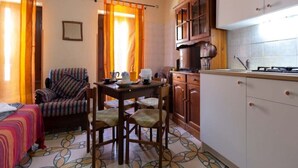 A compact kitchen with a dining area, featuring a table, chairs, and a stove. - Panorama Studio 'Casa a Chiazzetta' (Castelbuono)
