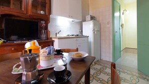 A kitchen with a coffee maker, cups, and a bowl of bread on the table. - Panorama Studio 'Casa a Chiazzetta' (Castelbuono)