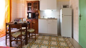 A compact kitchen with a dining area, a microwave, and a refrigerator. - Panorama Studio 'Casa a Chiazzetta' (Castelbuono)