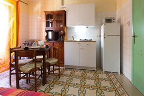 A compact kitchen with a dining area, a microwave, and a refrigerator.