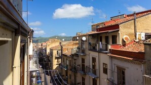 A narrow street with buildings on both sides, featuring balconies and satellite dishes. - Panorama Studio 'Casa a Chiazzetta' (Castelbuono)