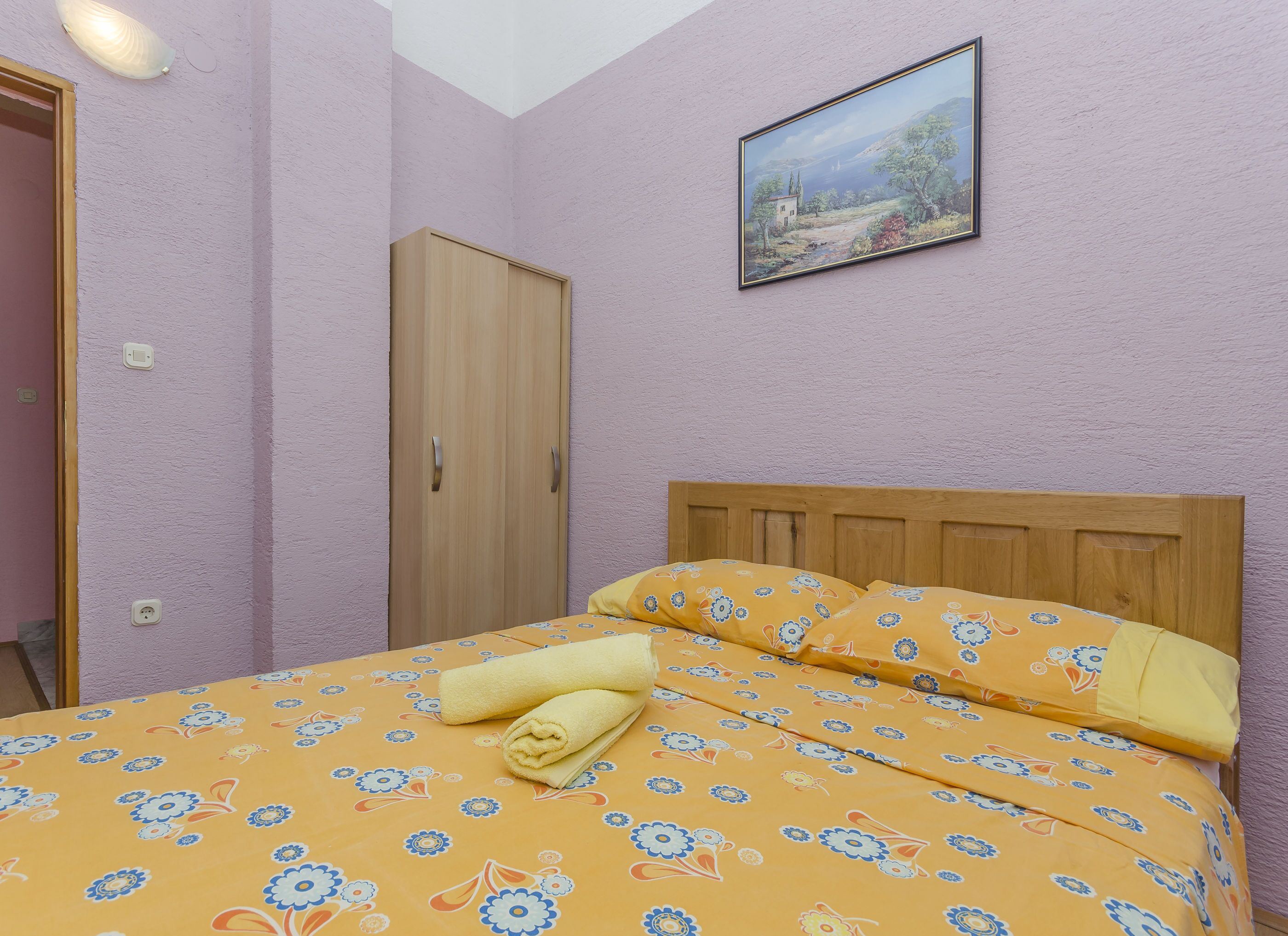 A bedroom with a bed, a wardrobe, and a painting on the wall.
