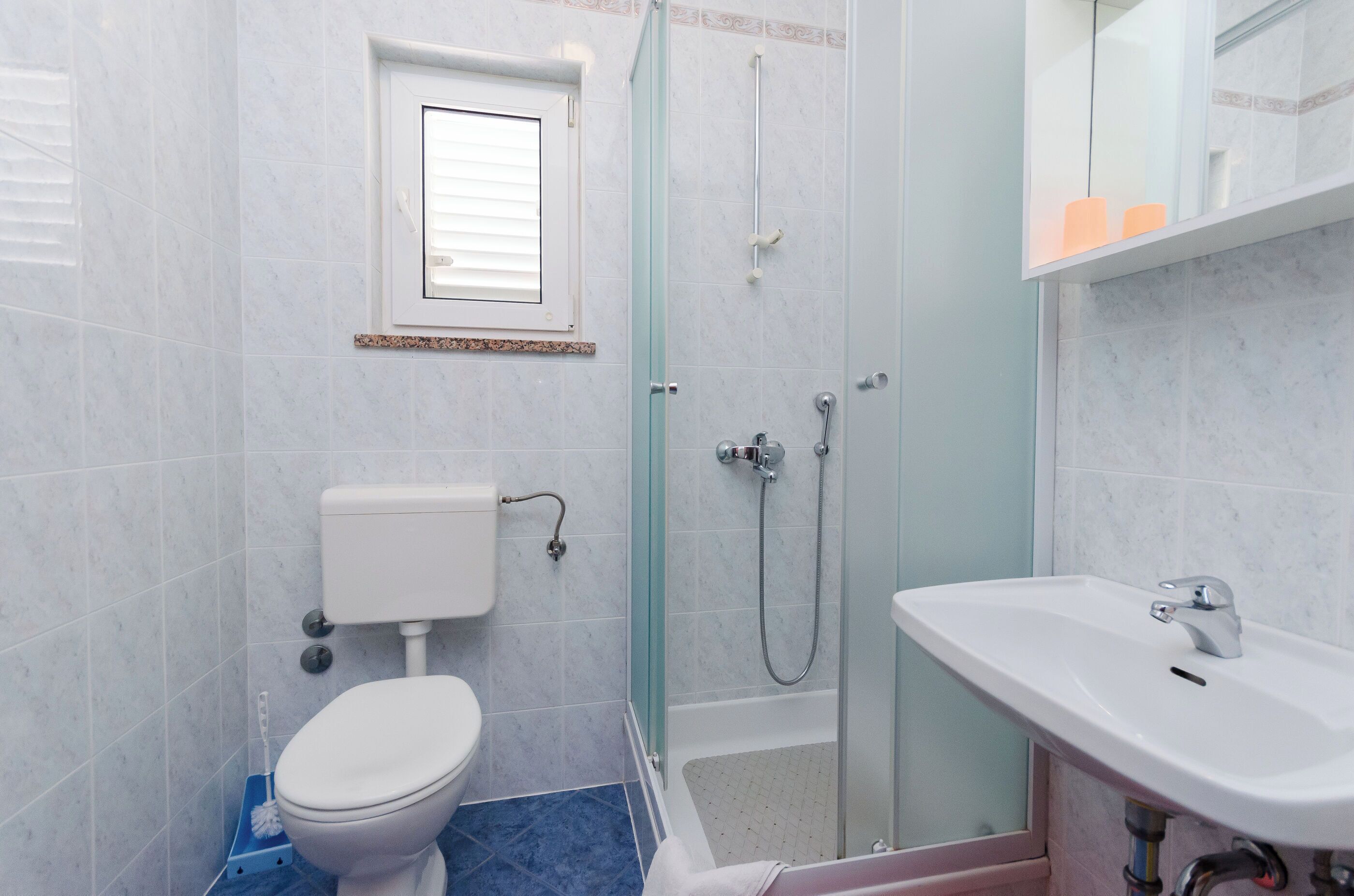 A bathroom with a toilet, shower, and sink.
