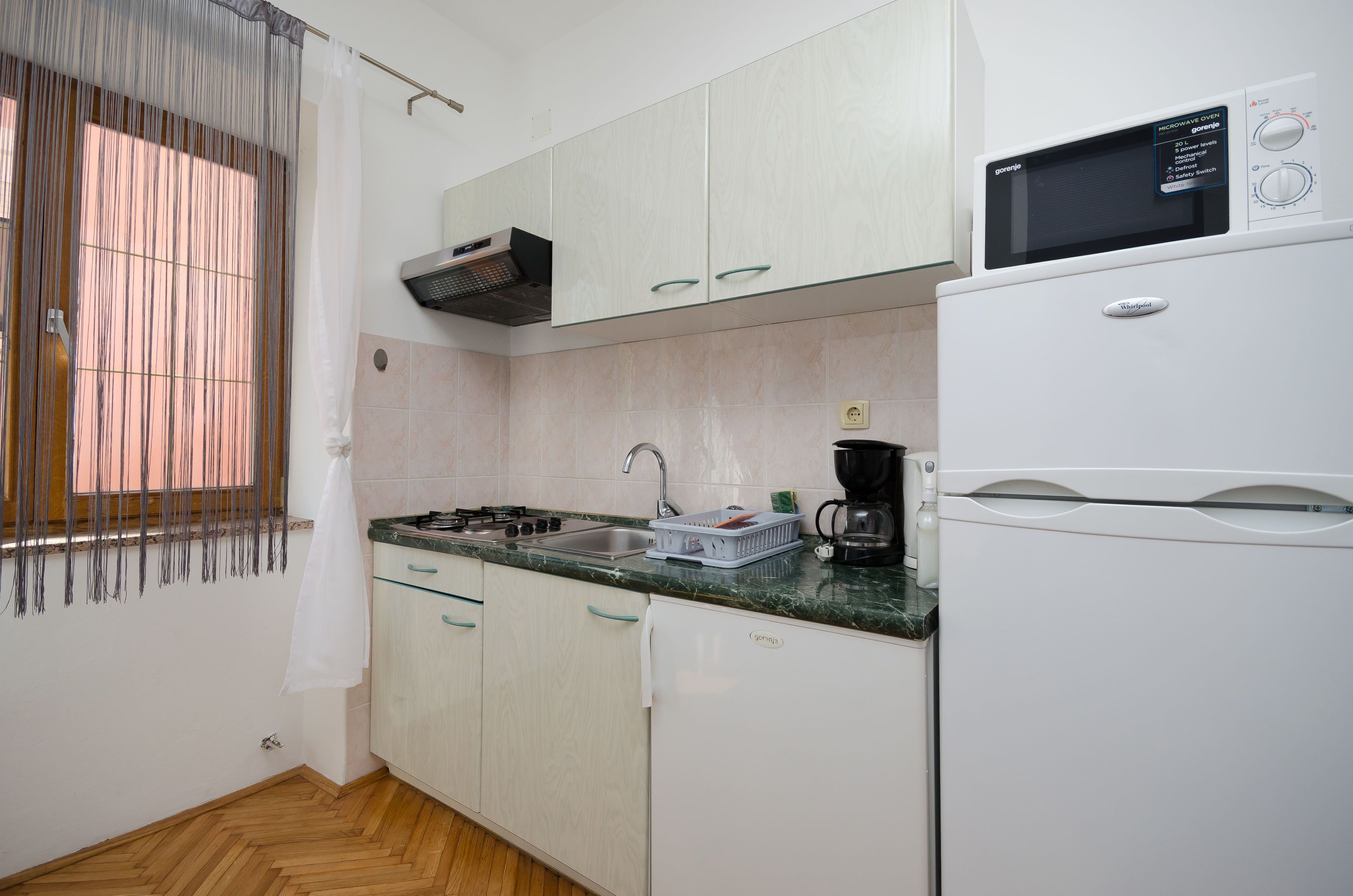 A compact kitchen with a microwave oven, a coffee maker, and a sink.