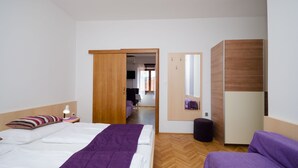 Ett modernt hotellrum med en säng, ett nattduksbord, en lila stol, en trägarderob och en spegel.