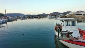 Un puerto deportivo con barcos amarrados, agua tranquila y un paisaje montañoso al fondo.