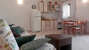 Un espace de vie compact comprenant un canapé, une petite table à manger et une kitchenette.