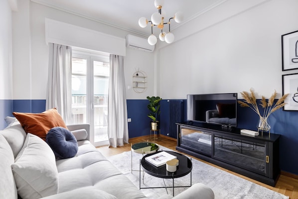 A modern living room with a sofa, television, and decorative items.