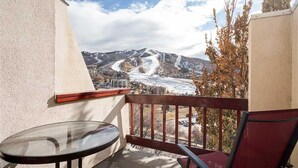 A balcony with a glass table and chair, overlooking a snowy mountain and a ski slope. - Storm Watch Condominiums - Sw205 (Steamboat Springs)