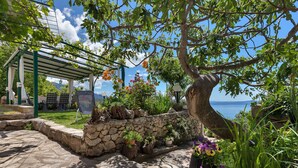 A covered outdoor seating area with stone walls and potted plants. - House Olive (Tucepi)