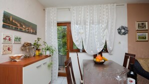 A dining area with a wooden table, chairs, a bottle of wine, and a bowl of fruit. - Apartment Marija (Palit)