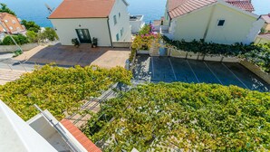 A residential building with a red-tiled roof, a small garden, and a view of the sea. - Apartments Jurko (Okrug Gornji)