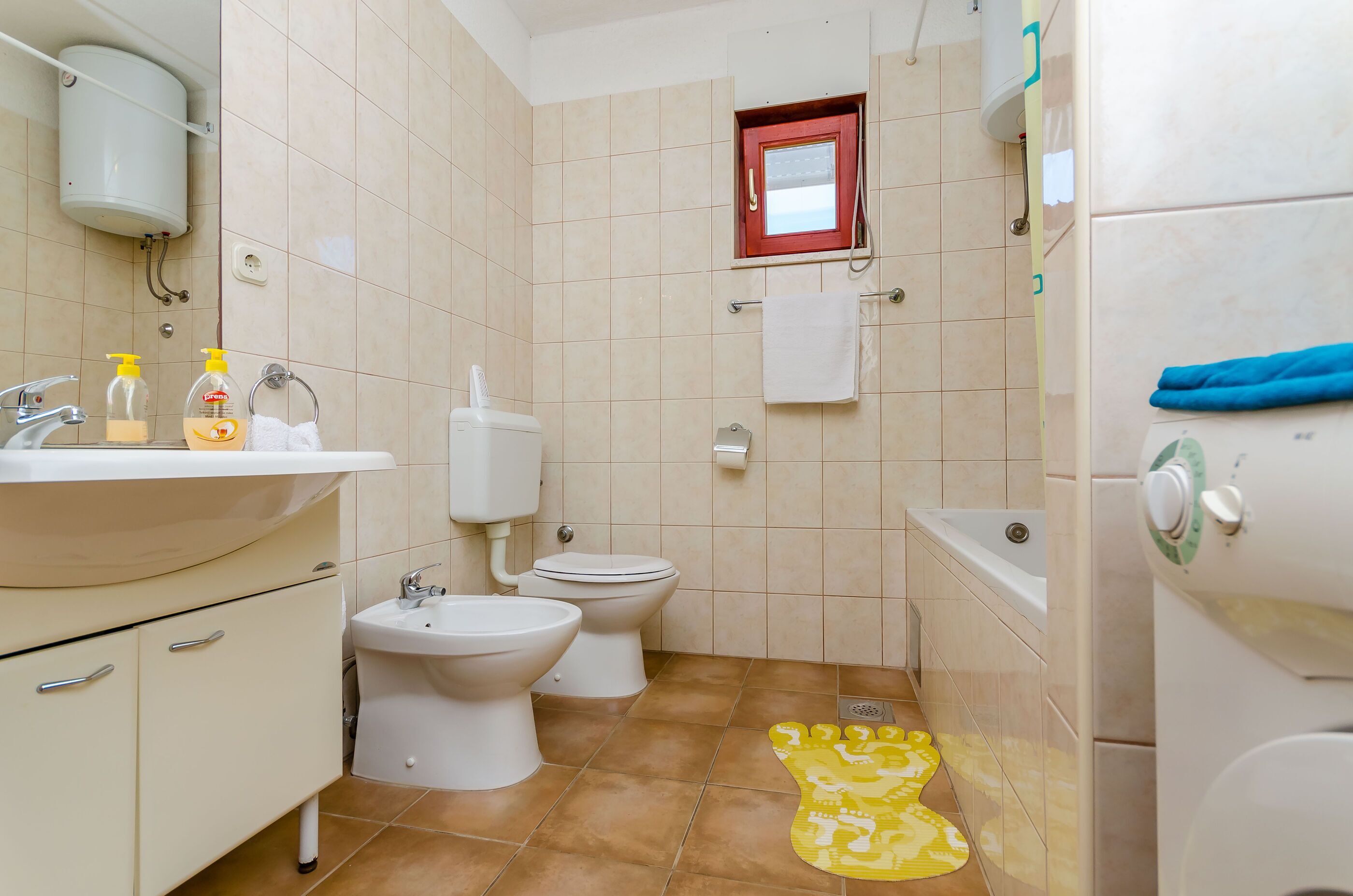 A bathroom with a sink, bidet, toilet, and bathtub.