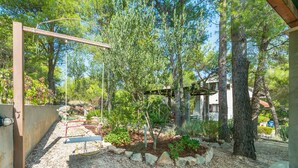 A garden with a swing set, trees, and a house in the background. - Apartment Ametist (Milna)