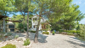 A house with a stone fireplace, surrounded by a gravel driveway and various plants. - Apartment Ametist (Milna)