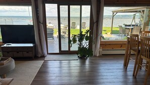 Une pièce dotée d’une grande porte-fenêtre coulissante donnant sur une terrasse aménagée avec du mobilier d’extérieur et offrant une vue sur l’eau.