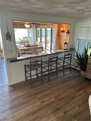 A kitchen with a wooden island, bar stools, and a view of the outdoors.