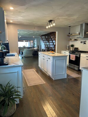 A modern kitchen with white cabinetry, a central island, and a built-in stove.